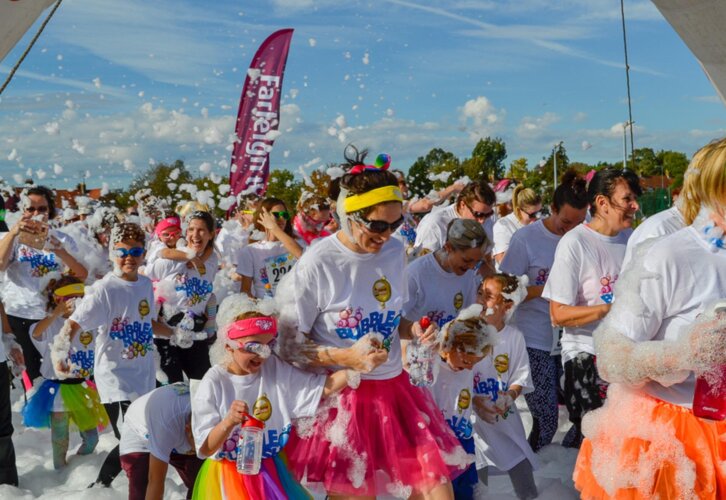 Crowd of people running through foam bubbles