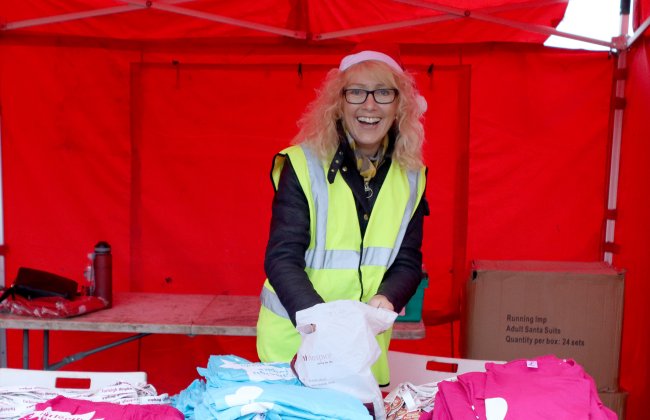 A volunteer helping distribute tshirts at the Santa fun run