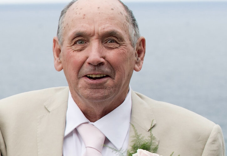 A portrait of Eric Cox smartly dressed in a cream suit with rose buttonhole for a wedding
