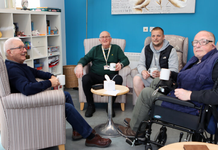 Mike Hubble Carer Champion sits with 3 other adult men in a lounge with the Lantern social drop in group
